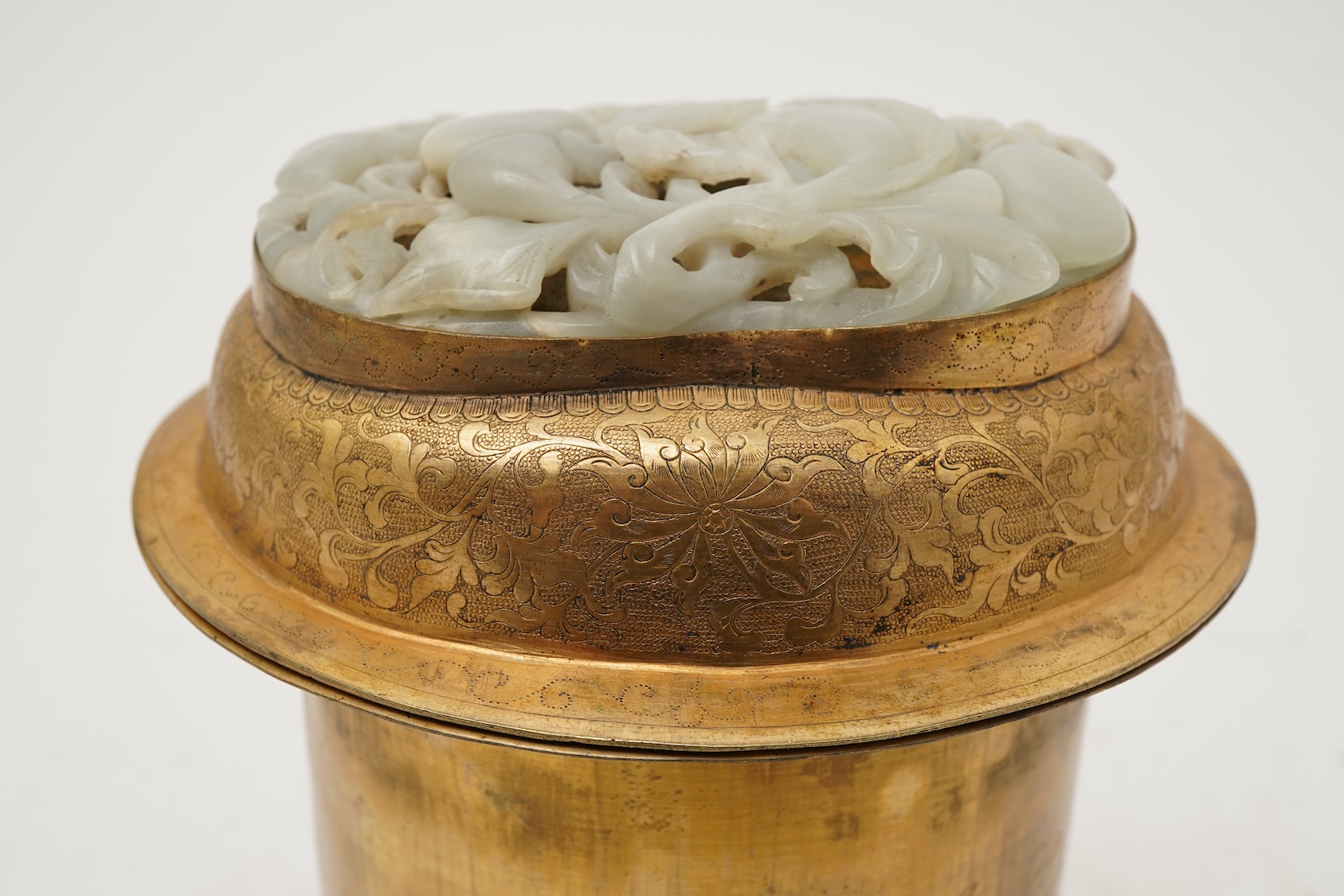 A Chinese pale celadon jade oval plaque, 17th/18th century, mounted on a late Qing gilt copper jar